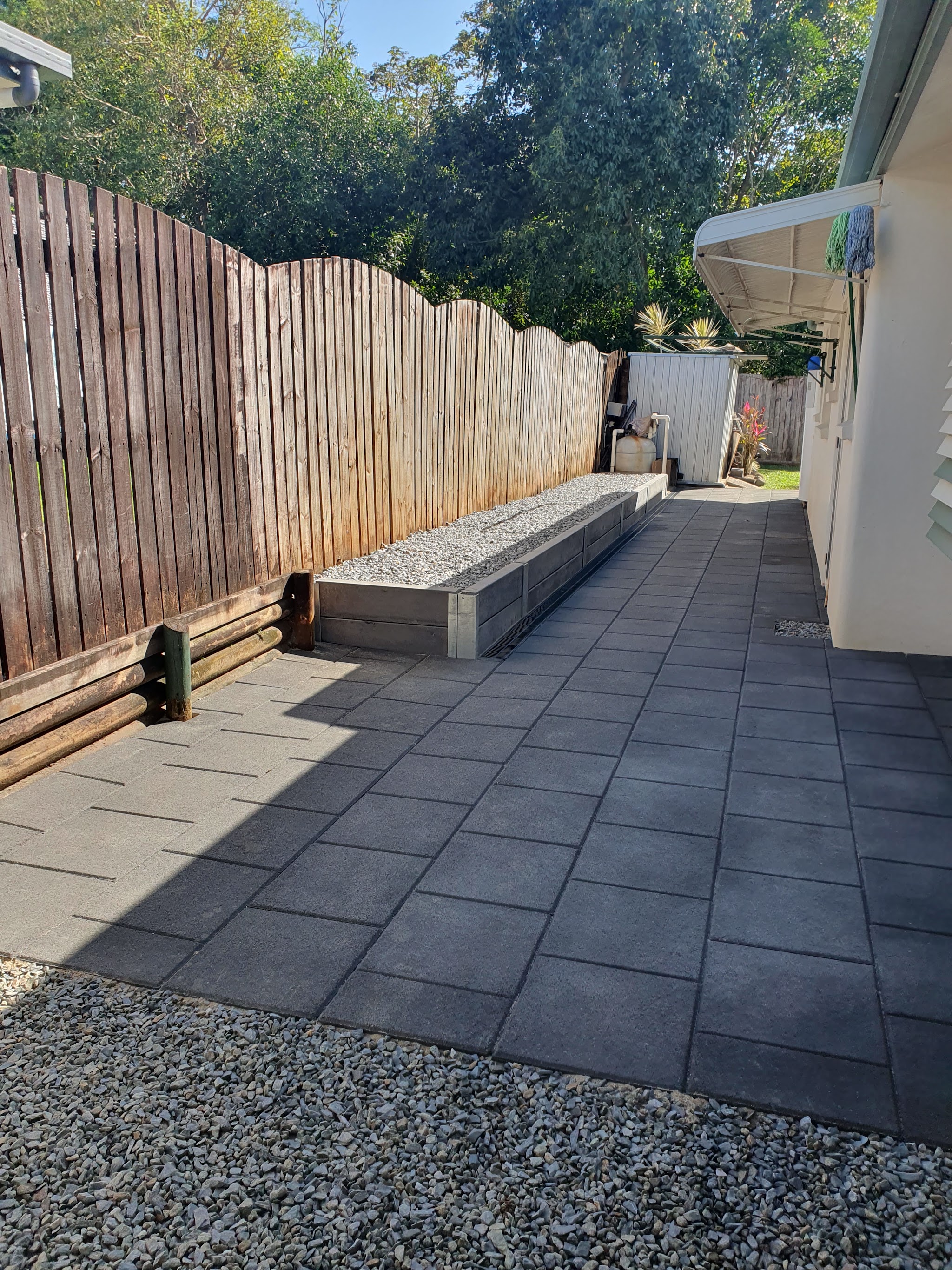 The finished side path, charcoal pavers laid with a gravel strip and a timber sleeper garden edge along the fence